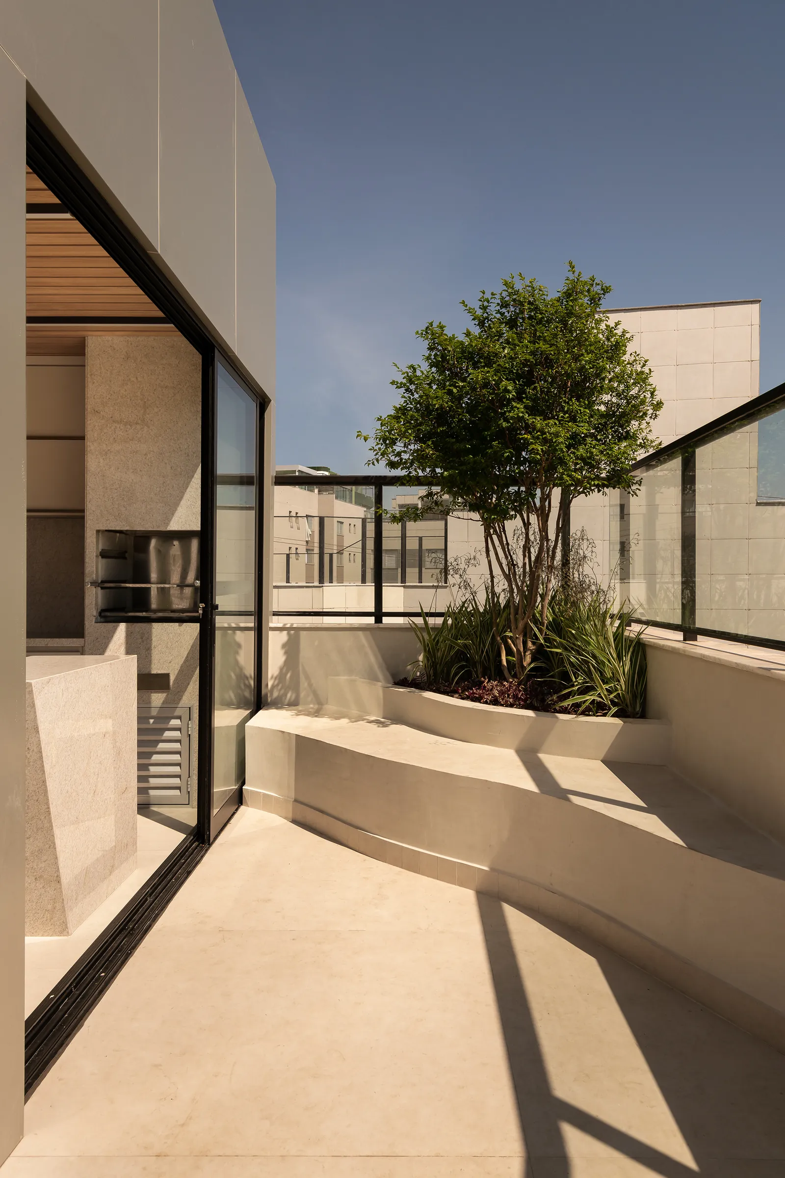 Terraço com árvore e guarda-corpo de vidro
